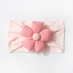 Gros plan d'un bandeau bébé en tricot rose avec grande fleur 3D et texture jacquard douce