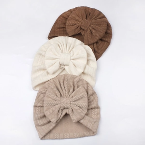 Three-pack ribbed baby turban hats with large bows in brown, cream, and khaki colors