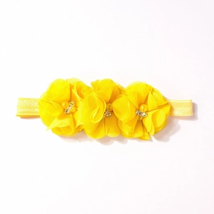 Dettaglio fiori in chiffon giallo con perle e strass su fascia per capelli bimba