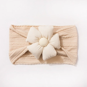 Détail du bandeau bébé en maille torsadée beige avec une fleur 3D douce et décorative