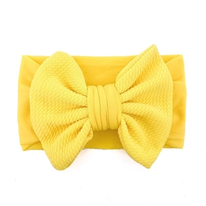 Detailed close-up of a bright yellow elastic baby headband with a large textured bow knot