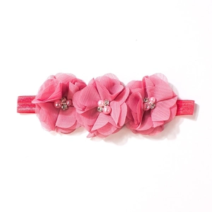 Dettaglio fascia neonata con fiori in chiffon rosa, perle e strass su banda elastica