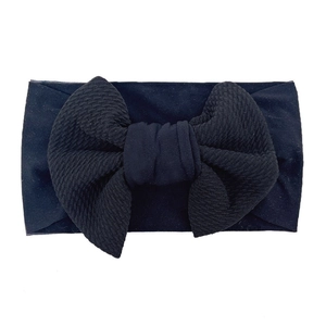 Detail view of baby bow headband showing waffle texture and soft black elastic fabric