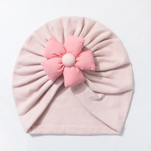 Detail of soft pink cotton baby turban cap featuring a decorative 3D fabric flower