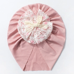 Détail d'un bonnet rose côtelé pour bébé avec un grand nœud en dentelle multicouche