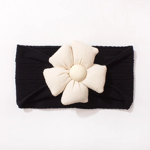 Détail d'un bandeau pour bébé en maille côtelée noire avec fleur en tissu blanc