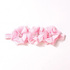 Dettaglio di fiori in chiffon rosa con perle e strass su fascia elastica per neonati