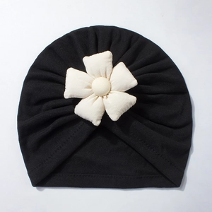 Detail of soft black baby turban hat featuring a large 3D white flower with beaded center