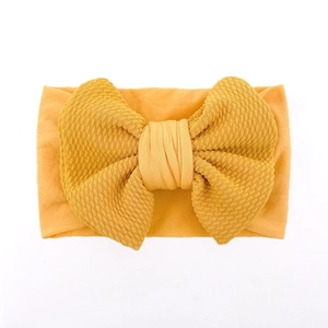 Detail of soft mustard yellow baby headband with textured fabric and large bow