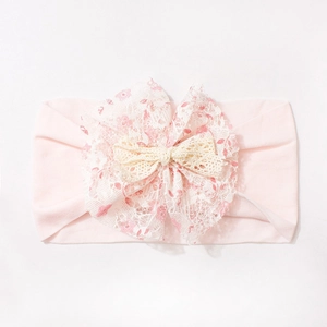 Close-up of pink baby nylon headband with layered floral lace bow and woven detail