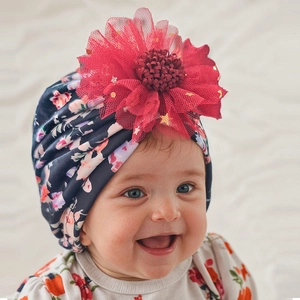 Detail of baby floral turban hat with a large 3D red mesh flower and golden sequins