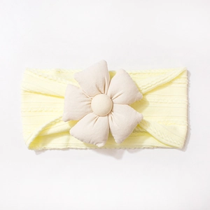 Gros plan détaillé du bandeau pour bébé en tricot jaune clair avec fleur 3D crème