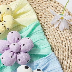 Detailed view of ribbed knit baby headbands with large polka dot 3D floral accents