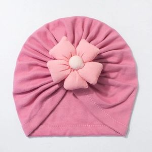 Detail of pink knitted baby hat with handmade fabric flower and double stitching