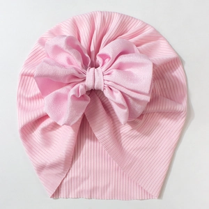 Detail of soft pink ribbed knit baby hat featuring a large layered chiffon bow decoration