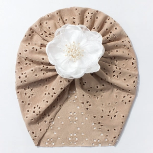Detail eines Baby-Turbans aus khaki Lochstrick mit großer weißer Satinblume und Perlen