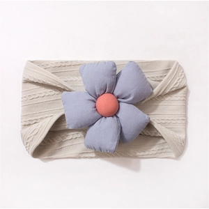 Détail d'un bandeau bébé en maille beige avec fleurs décoratives en tissu 3D colorées