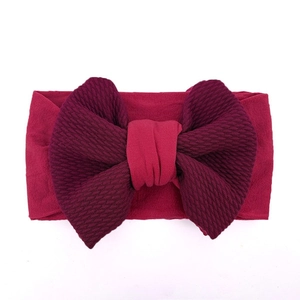 Close-up of soft burgundy baby headband with large waffle texture bow and elastic fabric