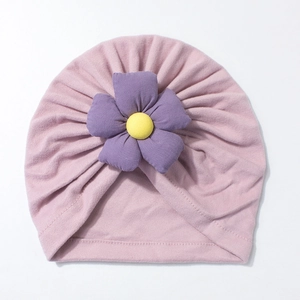 Close-up of baby turban hat in light pink with a purple 3D flower and soft knit texture