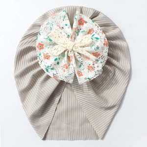 Détail du bonnet turban pour bébé en tissu côtelé taupe avec nœud floral décoratif