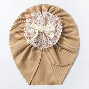 Détail du bonnet turban bébé kaki avec dentelle florale et nœud blanc élégant