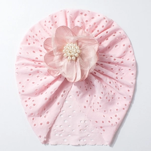 Detail von rosa durchbrochener Baby-Turbanmütze mit großer Organzablüte und Perlen