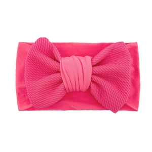 Macro detail of bright pink baby headband with textured ribbed bow design