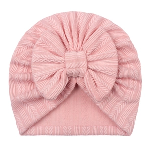 Detail of baby turban hat featuring pink striped knit fabric and a large soft bow