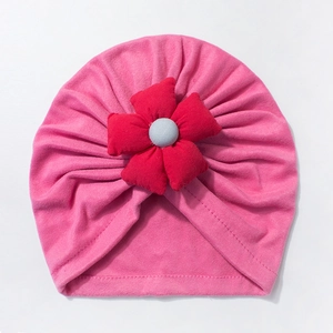 Detail of soft pink cotton baby beanie featuring a large red 3D floral decoration