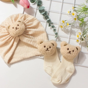 Beige baby knit hat and socks set featuring cute plush bear accents and ribbed textures