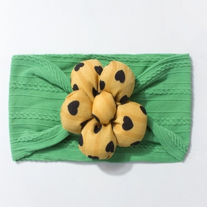 Cute green cable knit baby headband with a large yellow floral bow featuring heart patterns