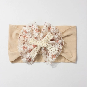 Detail of baby nylon headband featuring floral lace bow and soft knitted beige texture
