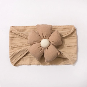 Détail d'un bandeau tricoté pour bébé beige avec une grande fleur 3D et perle centrale