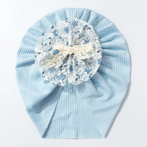 Détail d'un turban bébé en maille côtelée bleue avec décoration florale en dentelle fine