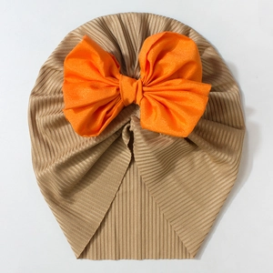 Detail of baby turban hat with a large orange bow on soft ribbed khaki fabric