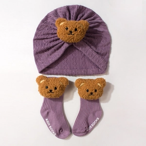 Detail of purple knitted baby headband hat and matching socks with cute brown plush bears