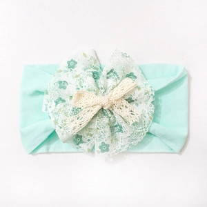 Detailed shot of mint green nylon headband with lace floral patterns and a soft knit bow
