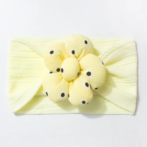 Detail of soft knitted yellow baby headband featuring a large floral daisy pattern