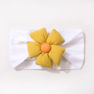 Gros plan sur un bandeau bébé en maille avec une grande fleur en tissu jaune et orange