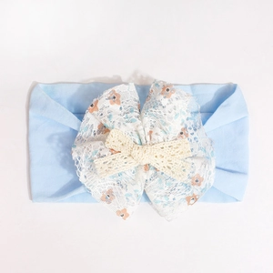 Detailed view of baby headband featuring floral lace bow and soft blue knit fabric