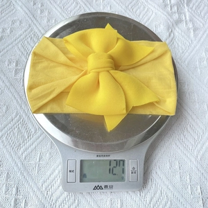 Detailed view showing the lightweight 12.7g yellow nylon bow headband on a scale