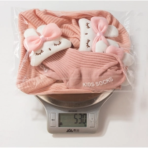 Ensemble bonnet et chaussettes bébé lapin rose pesant 53,0g sur une balance de précision