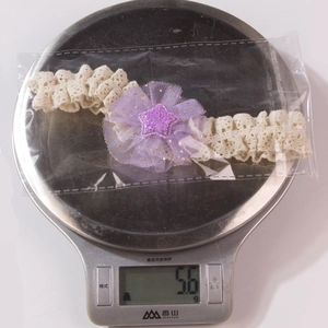 Dettaglio fascia in pizzo per neonati con fiore in rete viola e stella glitterata