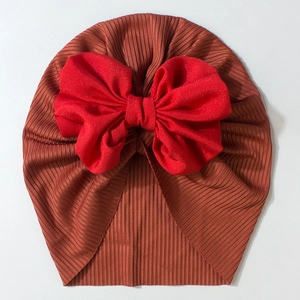 Detailed top view of soft ribbed baby turban hat with a large red bow decoration