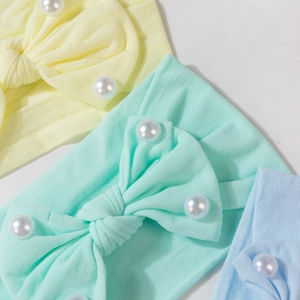 Dettaglio di fasce in maglia per neonati con fiocchi e perle finte bianche in colori pastello