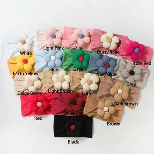 Flat lay of 18 colorful knit baby headbands with floral accents on white background