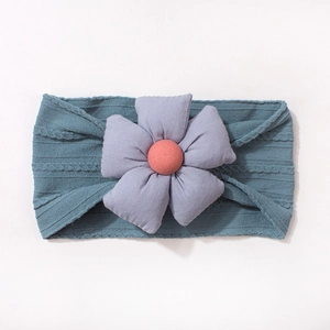 Détail d'un bandeau bébé en maille côtelée douce orné d'une grande fleur en tissu 3D