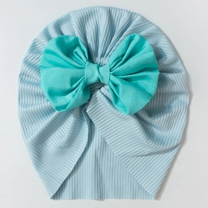 Detailed view of soft ribbed knit baby turban hat featuring a large turquoise bow accent