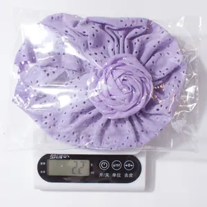 Mesure du poids d'un bonnet bébé ajouré violet clair avec rose en tissu sous emballage