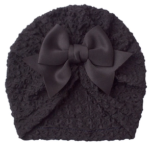 Close-up of black waffle fabric baby turban hat featuring a large satin bow detail